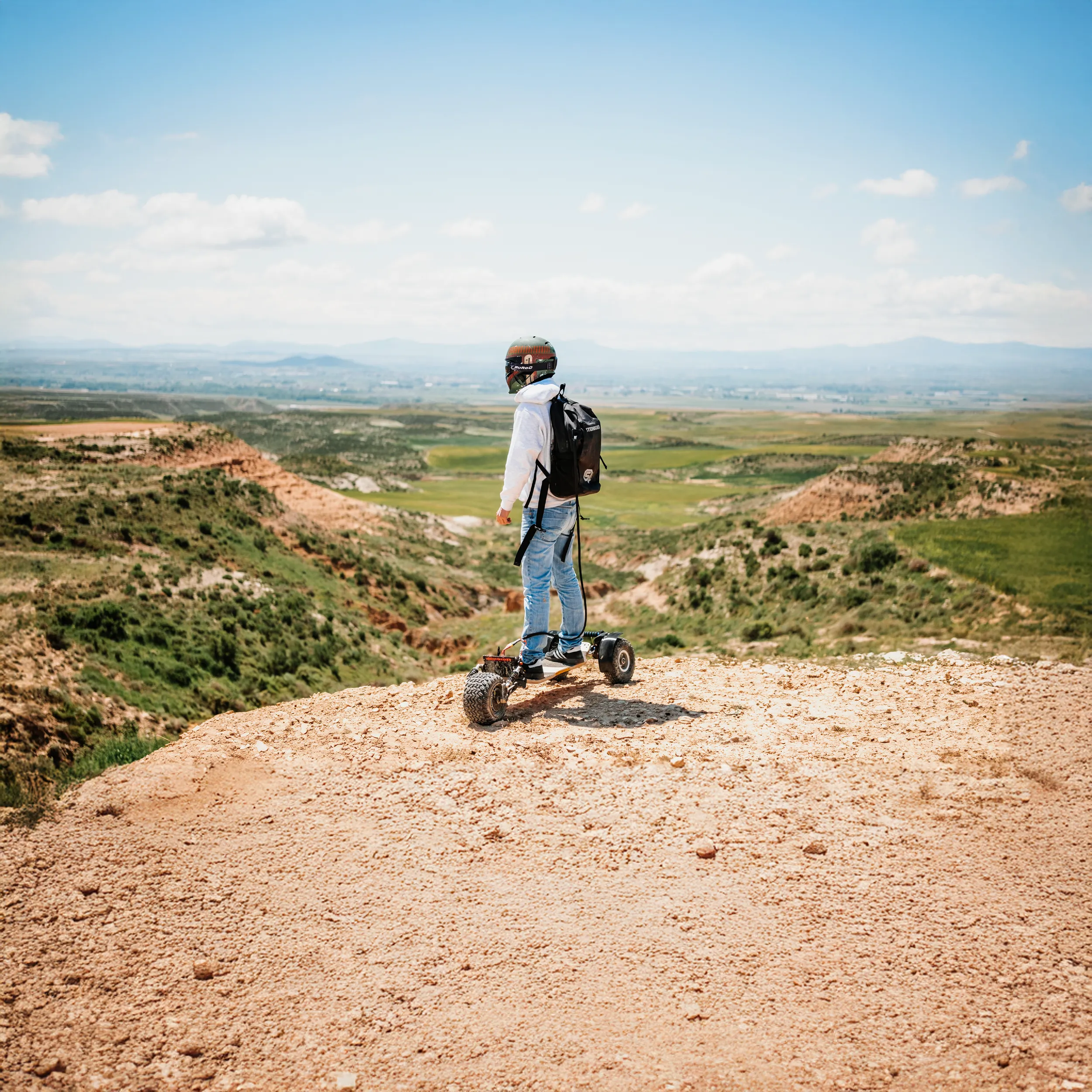 Rider équipé casque sur Sternboard contemplant panorama montagneux avec batterie intégrée au dos