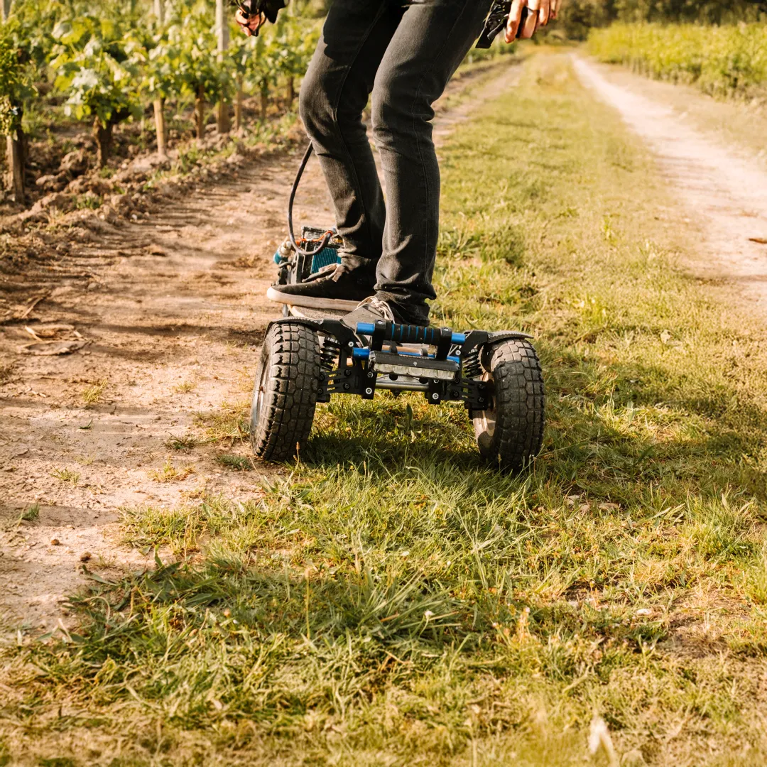 Rider Sternboard naviguant chemin vignoble entre terre et herbe avec skateboard électrique trois roues