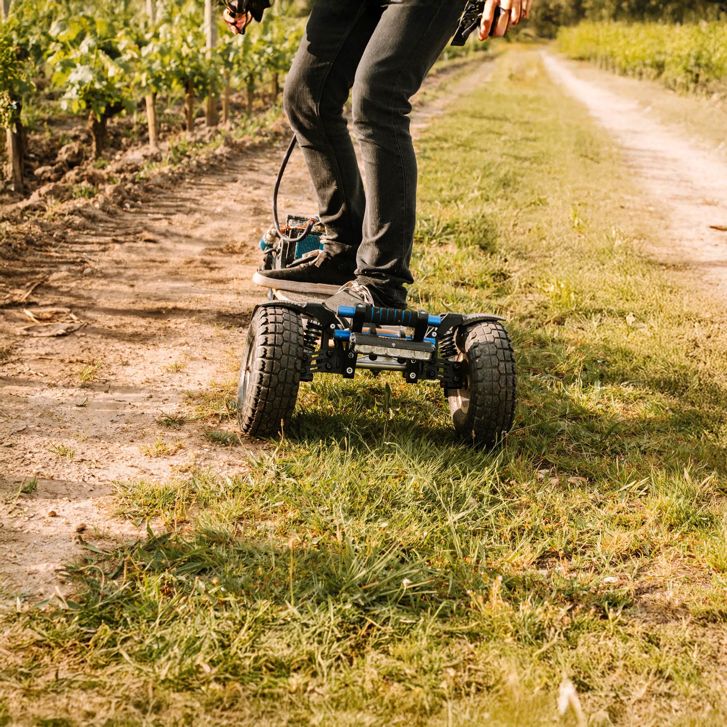 Rider Sternboard naviguant chemin vignoble entre terre et herbe avec skateboard électrique trois roues