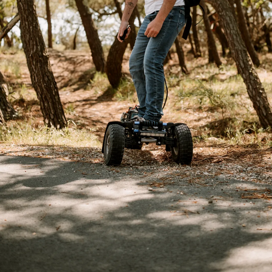 Rider Sternboard naviguant chemin forestier avec skateboard électrique trois roues tout-terrain