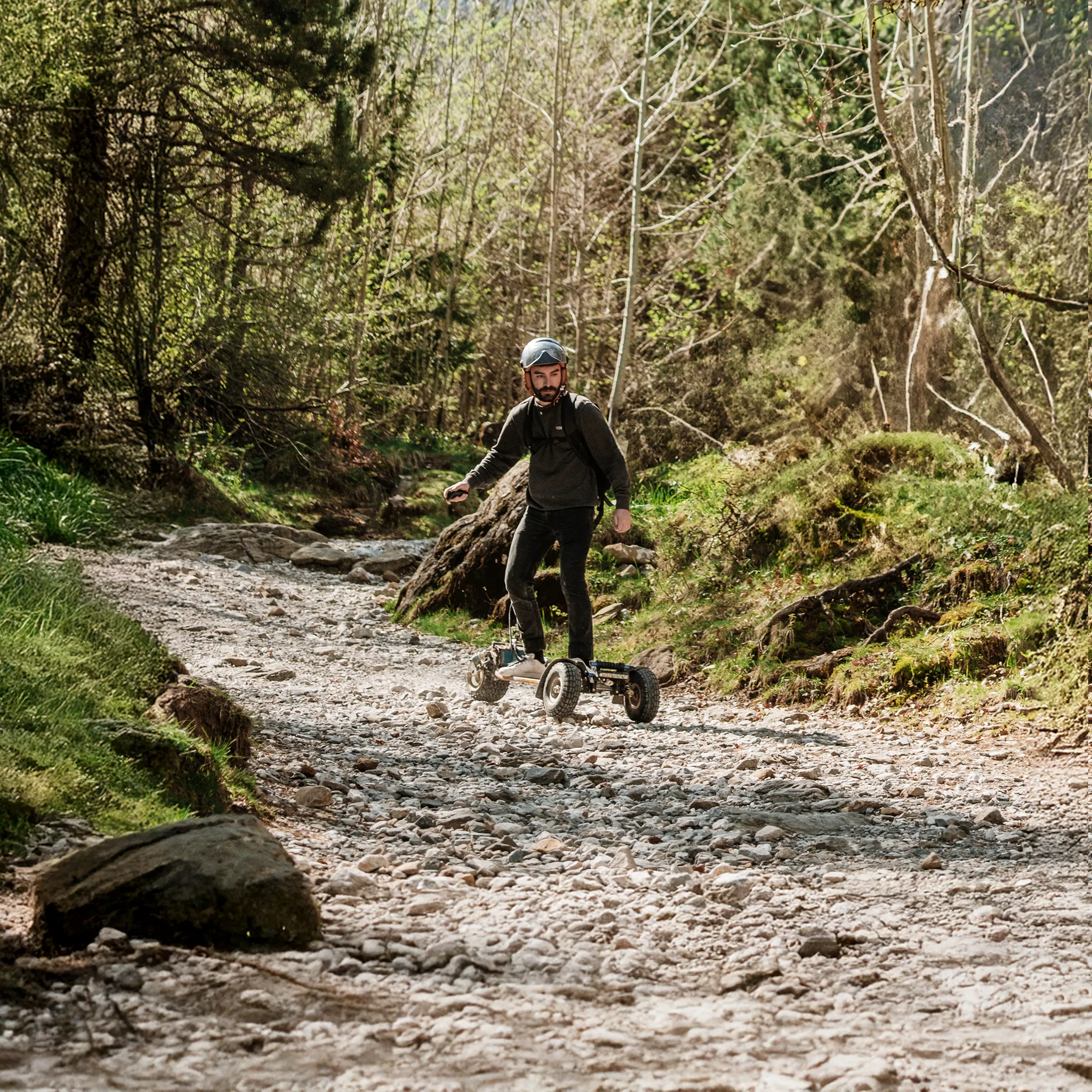 Rider casqué sur Sternboard traversant lit rivière caillouteux en milieu forestier naturel